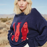 Close-up of the red fish sardine motif on the Marina Fish Knit Sweater — playful pattern on soft navy knit fabric.