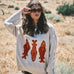 Woman wearing the Marina Fish Knit Sweater in sand — chunky oversized knit with playful red fish sardine motif