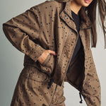 Front view of model wearing Miou Muse cocoa-brown jacket with black polka dots and a funnel neck