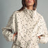 Front view of MIOU MUSE ecru jacket with black polka dots, a funnel neck, and a cropped boxy fit