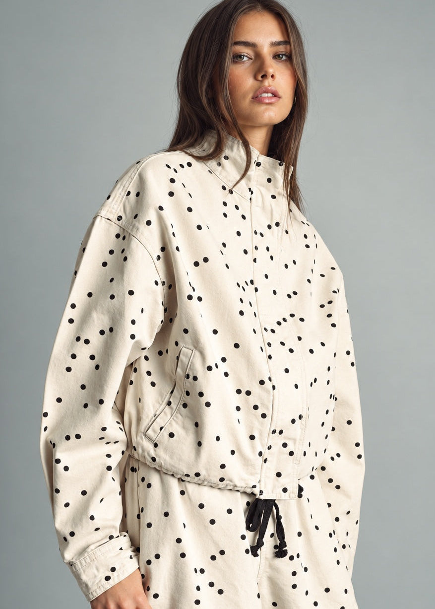 Side view of MIOU MUSE ecru and black polka dot jacket showing its relaxed fit and drawstring hem