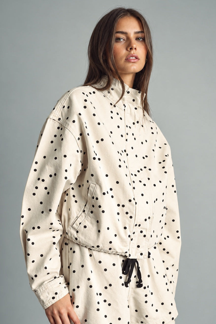 Side view of MIOU MUSE ecru and black polka dot jacket showing its relaxed fit and drawstring hem