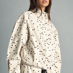 Side view of MIOU MUSE ecru and black polka dot jacket showing its relaxed fit and drawstring hem