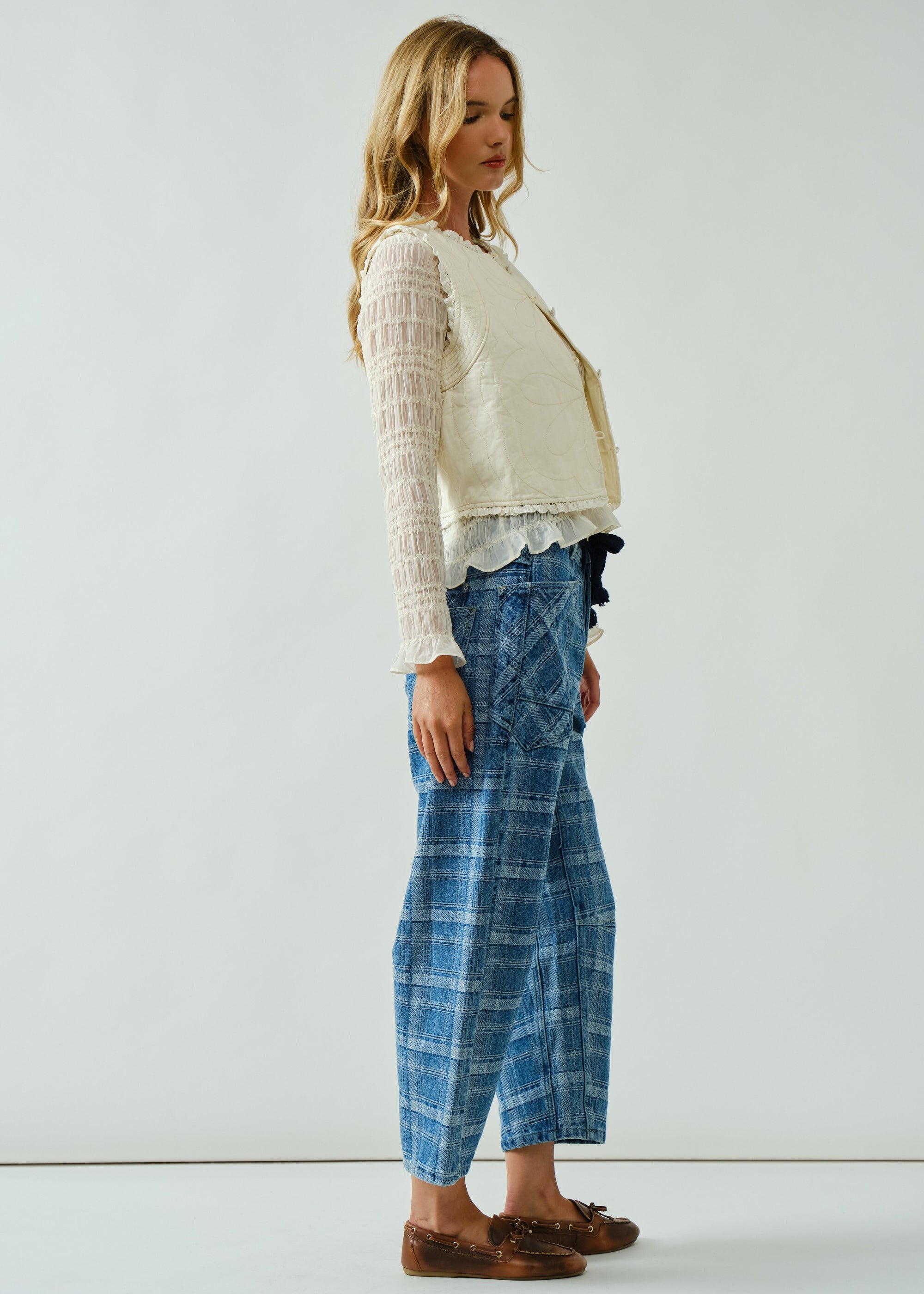 Model is wearing Moxie Jeans. Side view of the blue plaid barrel jeans highlighting relaxed silhouette