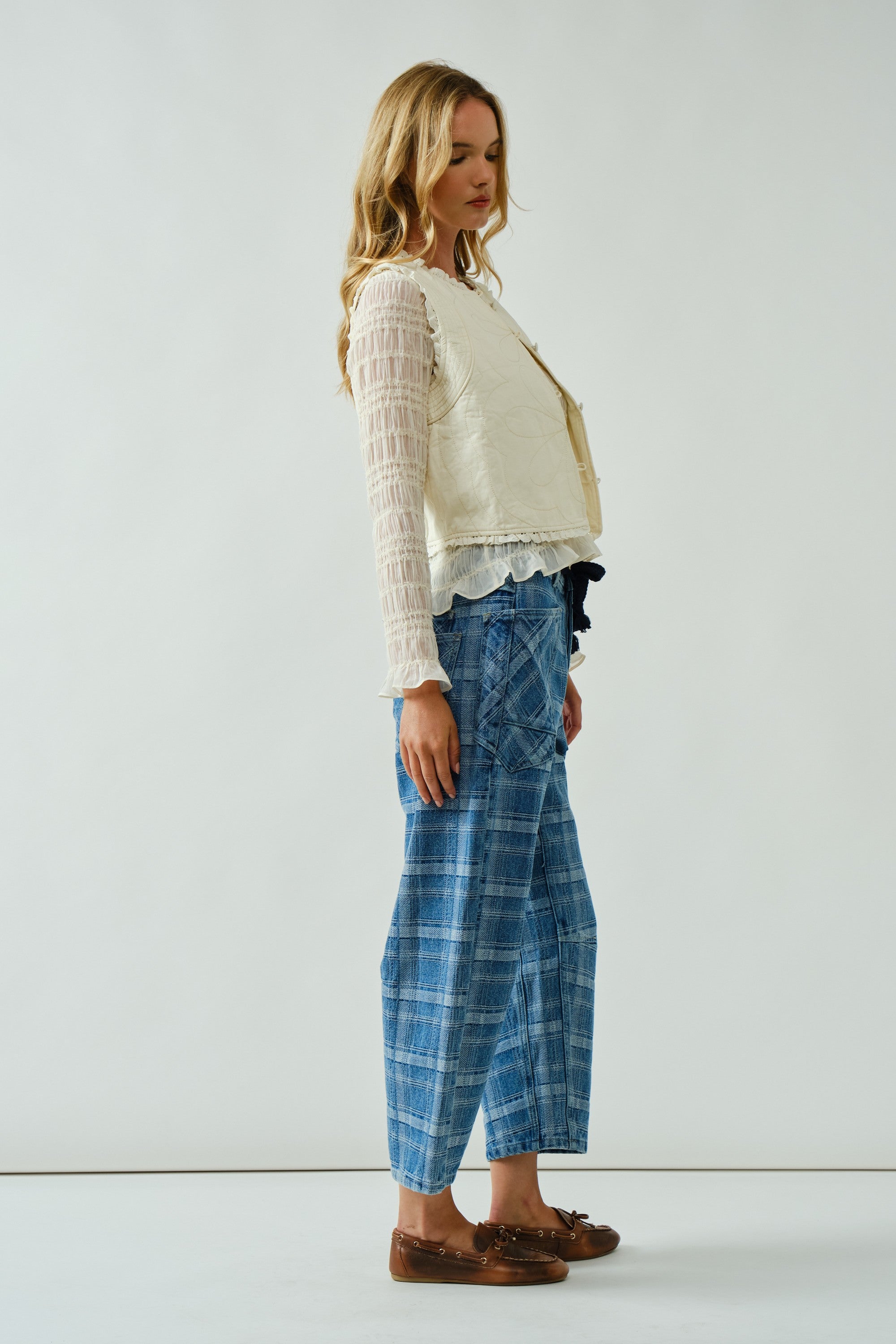 Model is wearing Moxie Jeans. Side view of the blue plaid barrel jeans highlighting relaxed silhouette