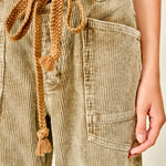 Close-up of Moxie Barrel Eyelet Jeans in corduroy camel showing the waist eyelet detail, corded drawstrings, deep pocket, and soft cotton corduroy fabric.