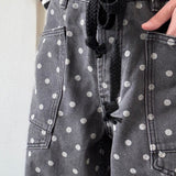 Close-up front detail of Moxie Barrel Eyelet Jeans in Polka Dot Black featuring eyelet waist detail, corded drawstring, and polka dot denim.