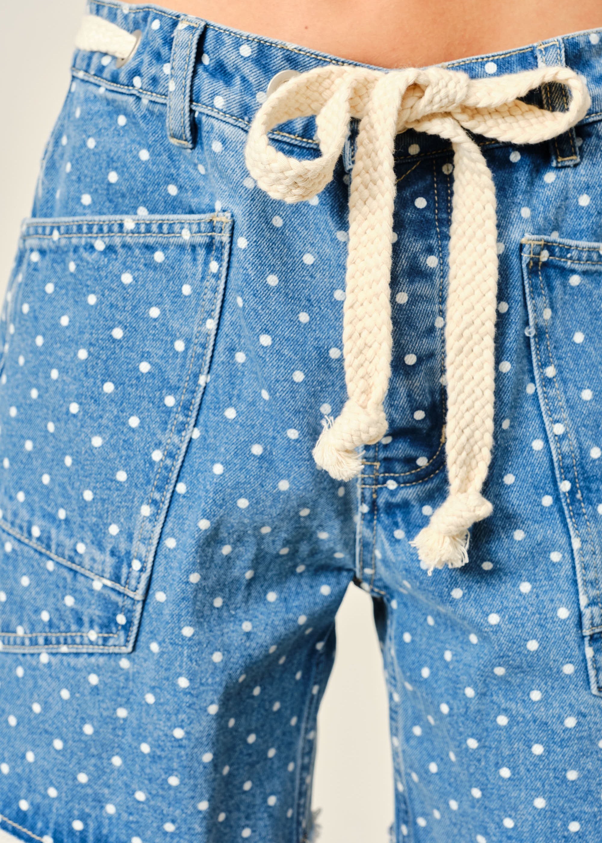Close-up of Moxie Barrel Shorts in Denim Dot showing the drawstring waist, eyelet detail, polka dot denim, and front snap closure.