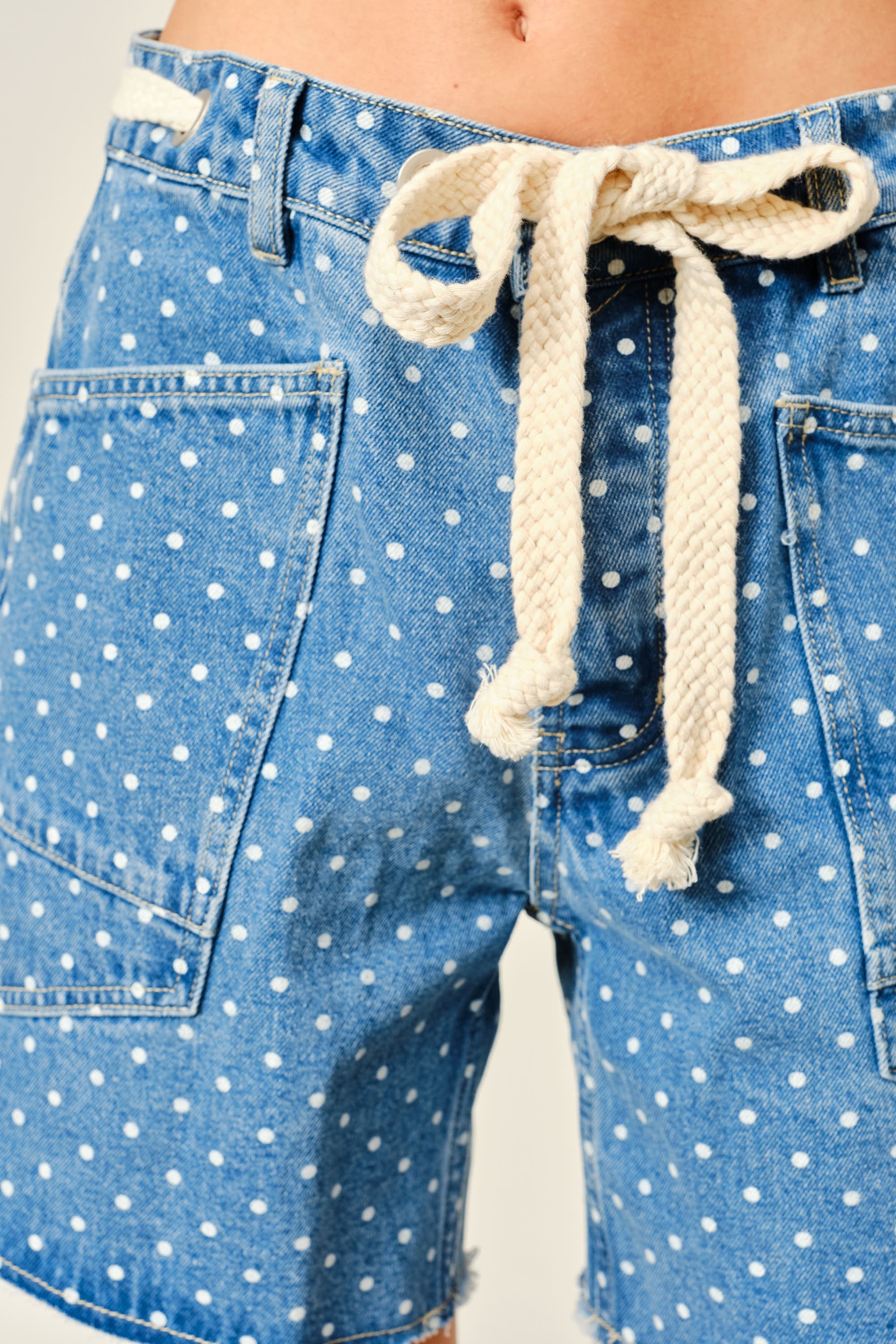 Close-up of Moxie Barrel Shorts in Denim Dot showing the drawstring waist, eyelet detail, polka dot denim, and front snap closure.