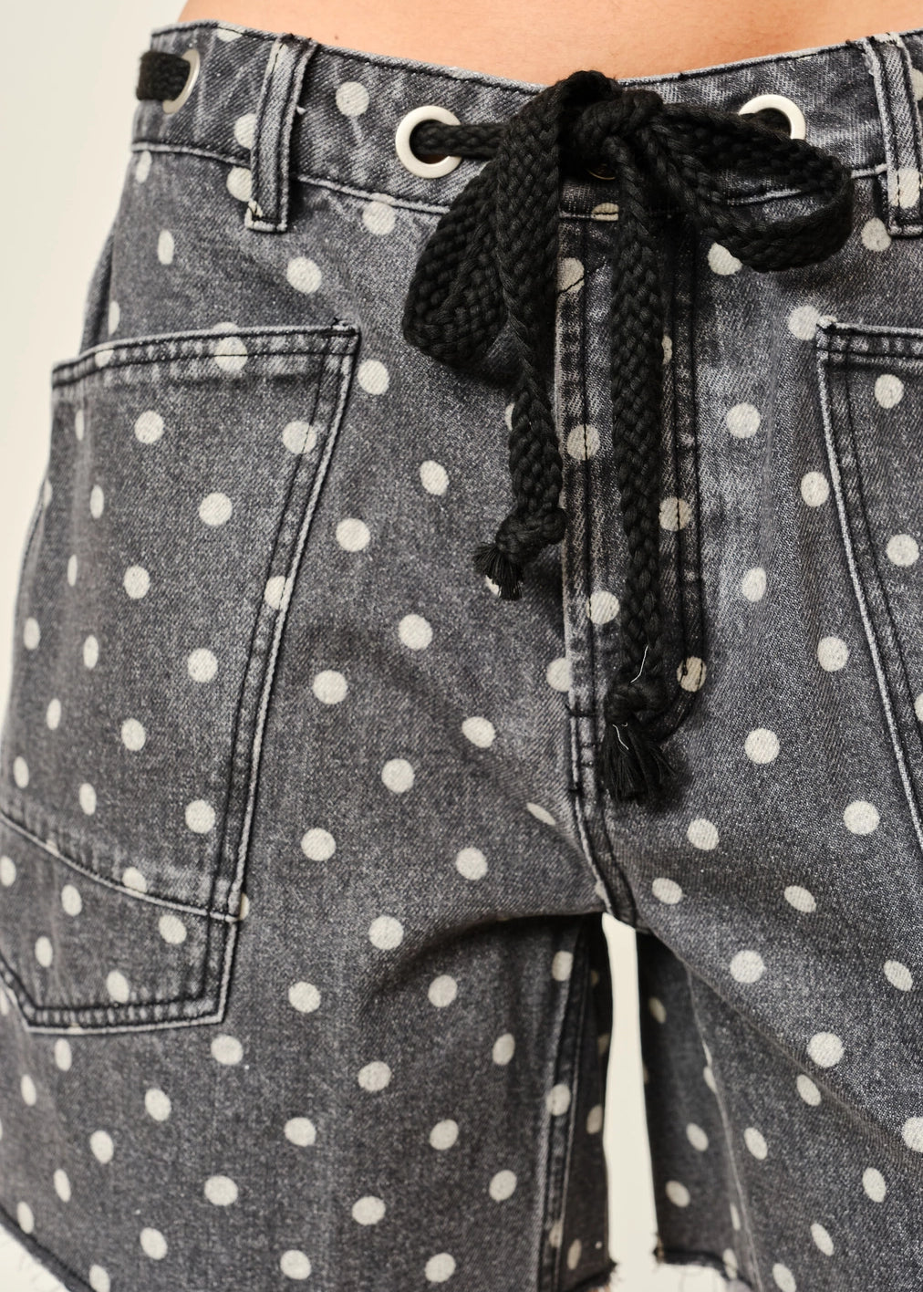 Gray denim shorts with white polka dots and a black drawstring.