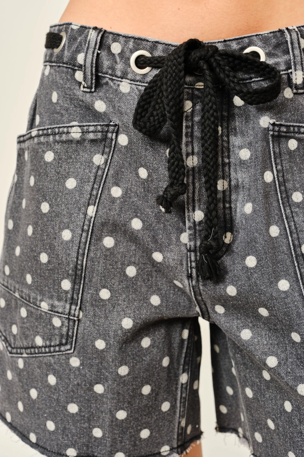 Gray denim shorts with white polka dots and a black drawstring.