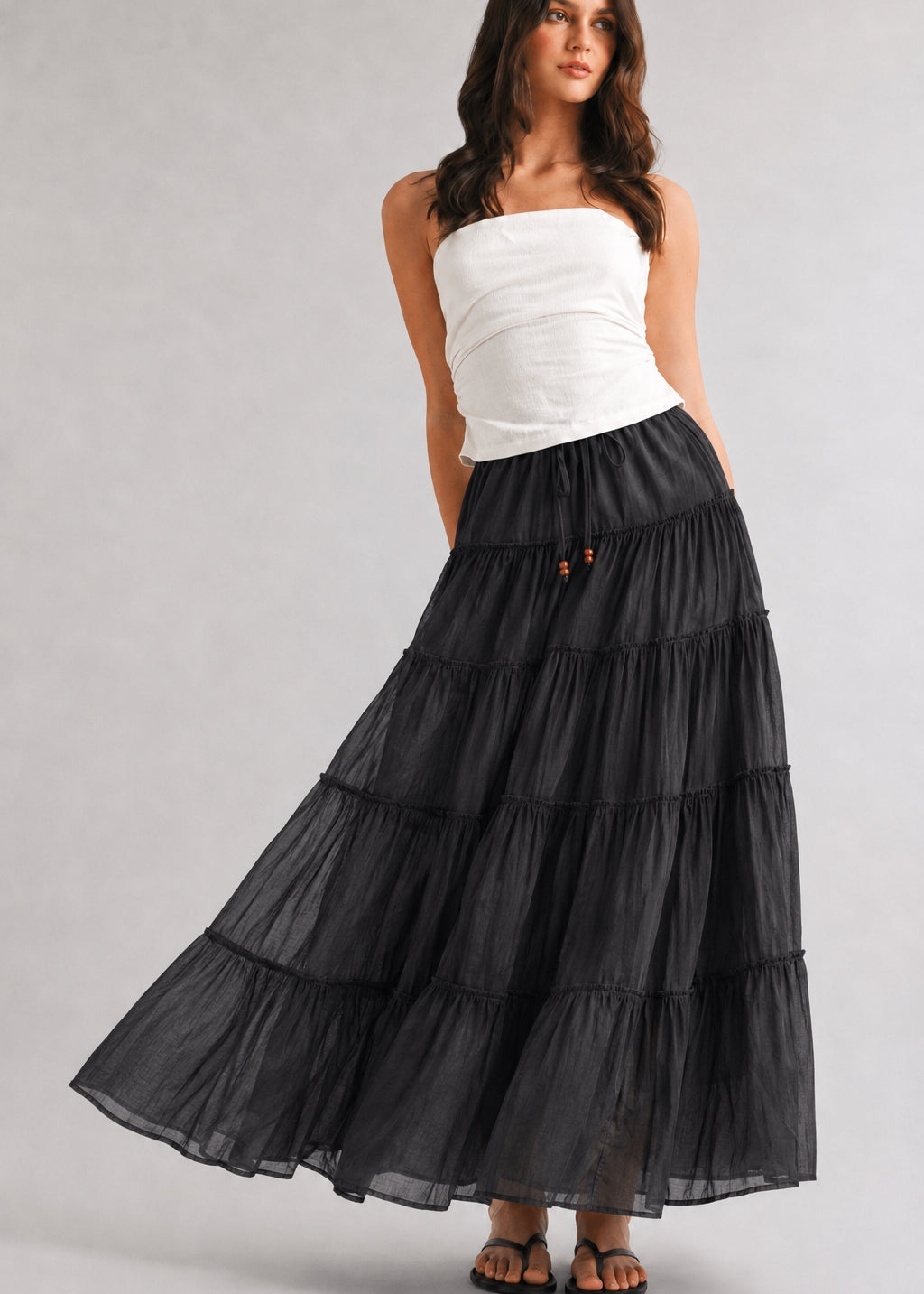 One Brynn cotton tiered maxi skirt in black styled with a white strapless top and sandals