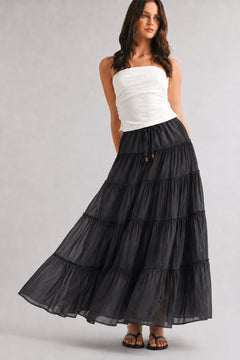 One Brynn cotton tiered maxi skirt in black styled with a white strapless top and sandals