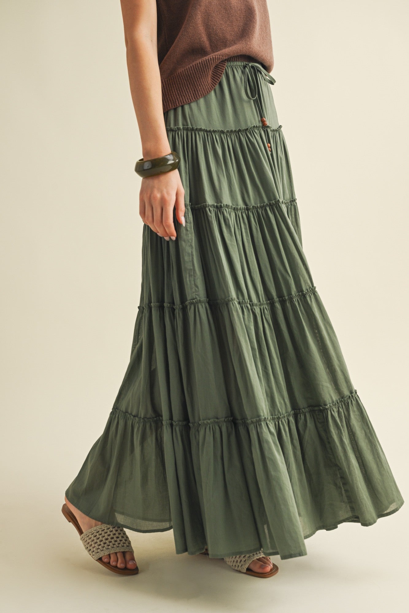 Green tiered skirt worn by a person on a beige background