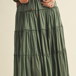 Green tiered skirt worn by a person on a beige background
