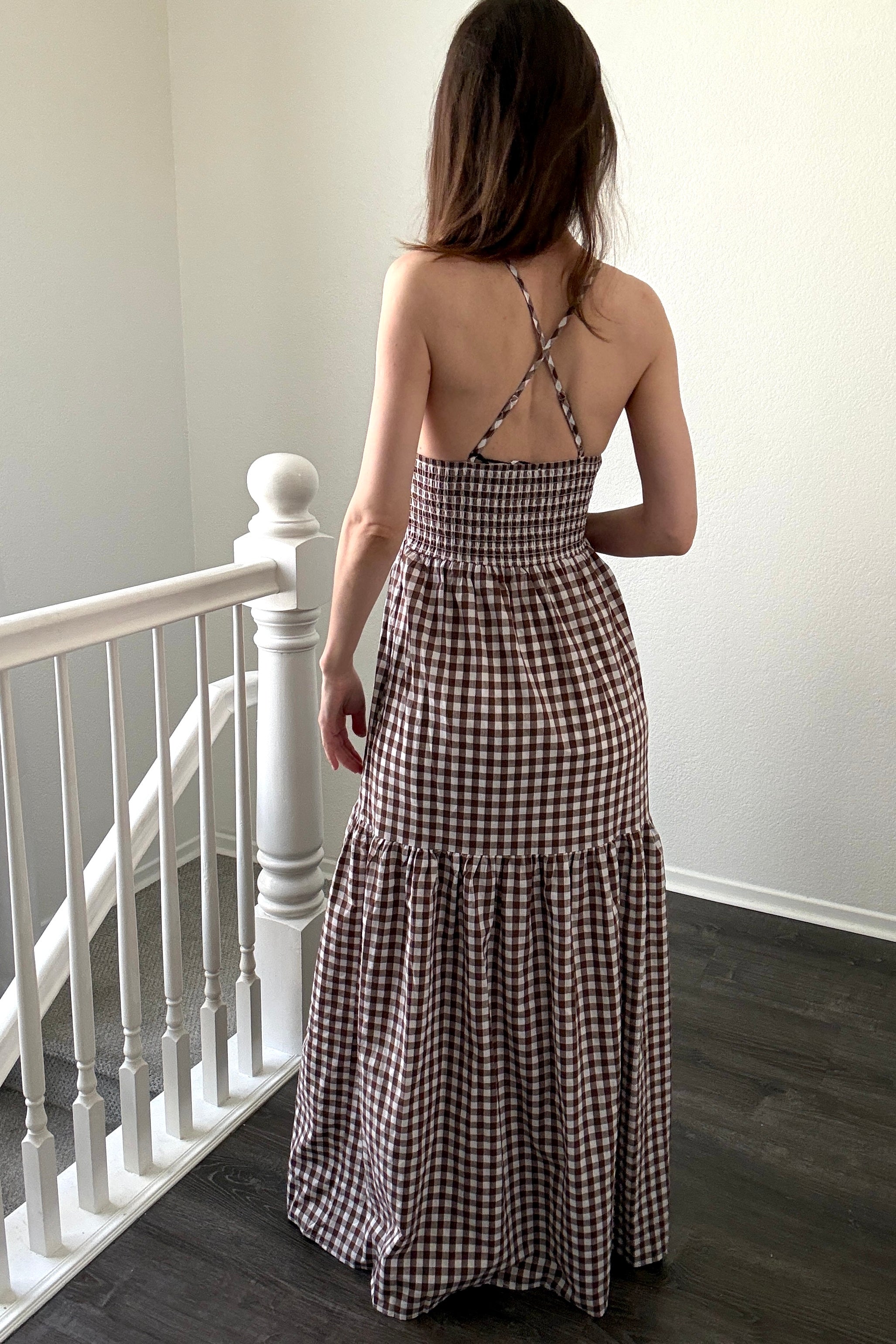 Back view of brown gingham maxi dress with smocked elastic back and crisscross straps