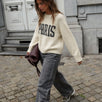 Woman styling the cream Paris graphic sweater with gray wide-leg jeans