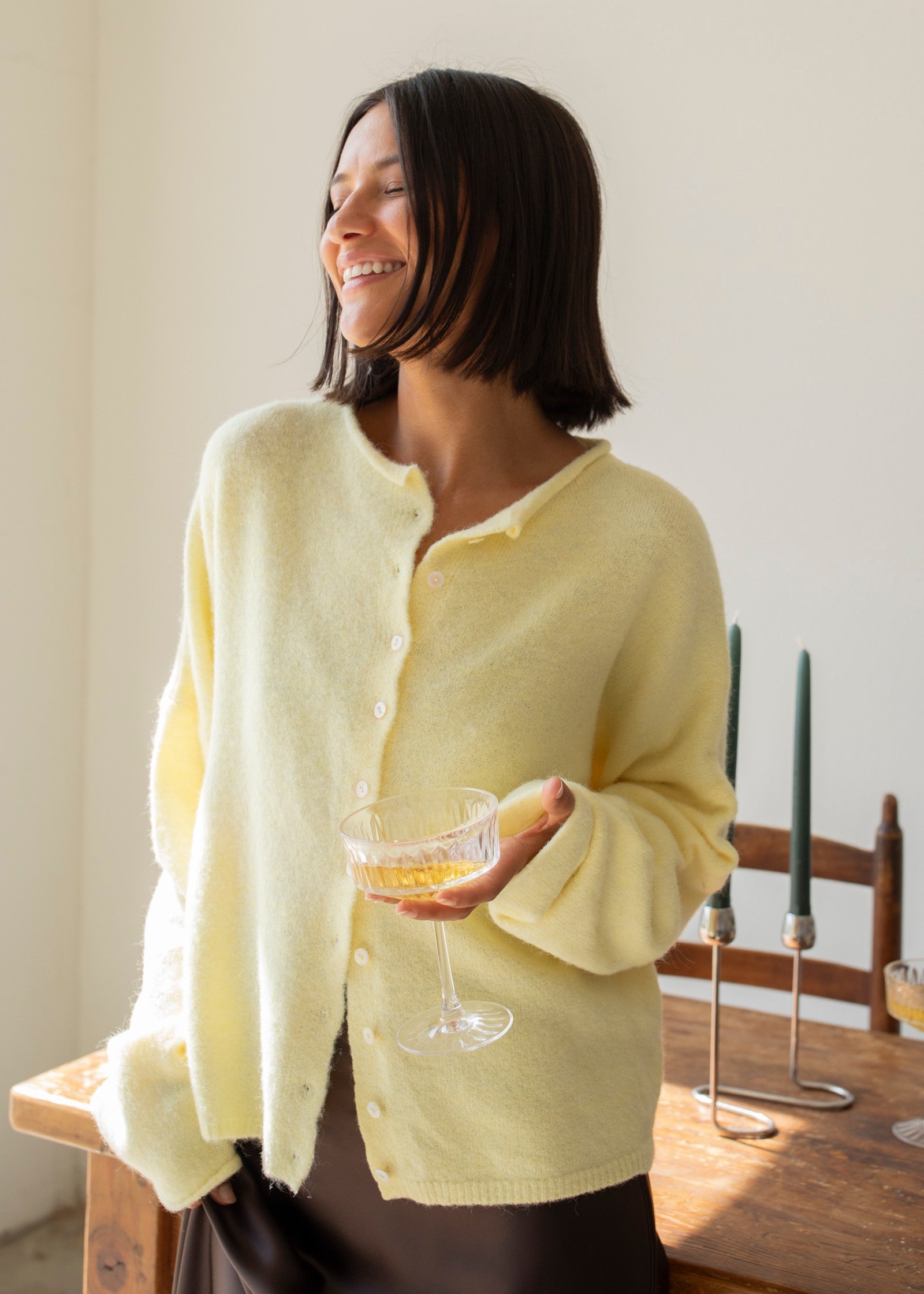 Woman wearing the Hailey Button Down Cardigan, also known as the Piper Cardigan — soft yellow lightweight knit with button front and rolled edges.