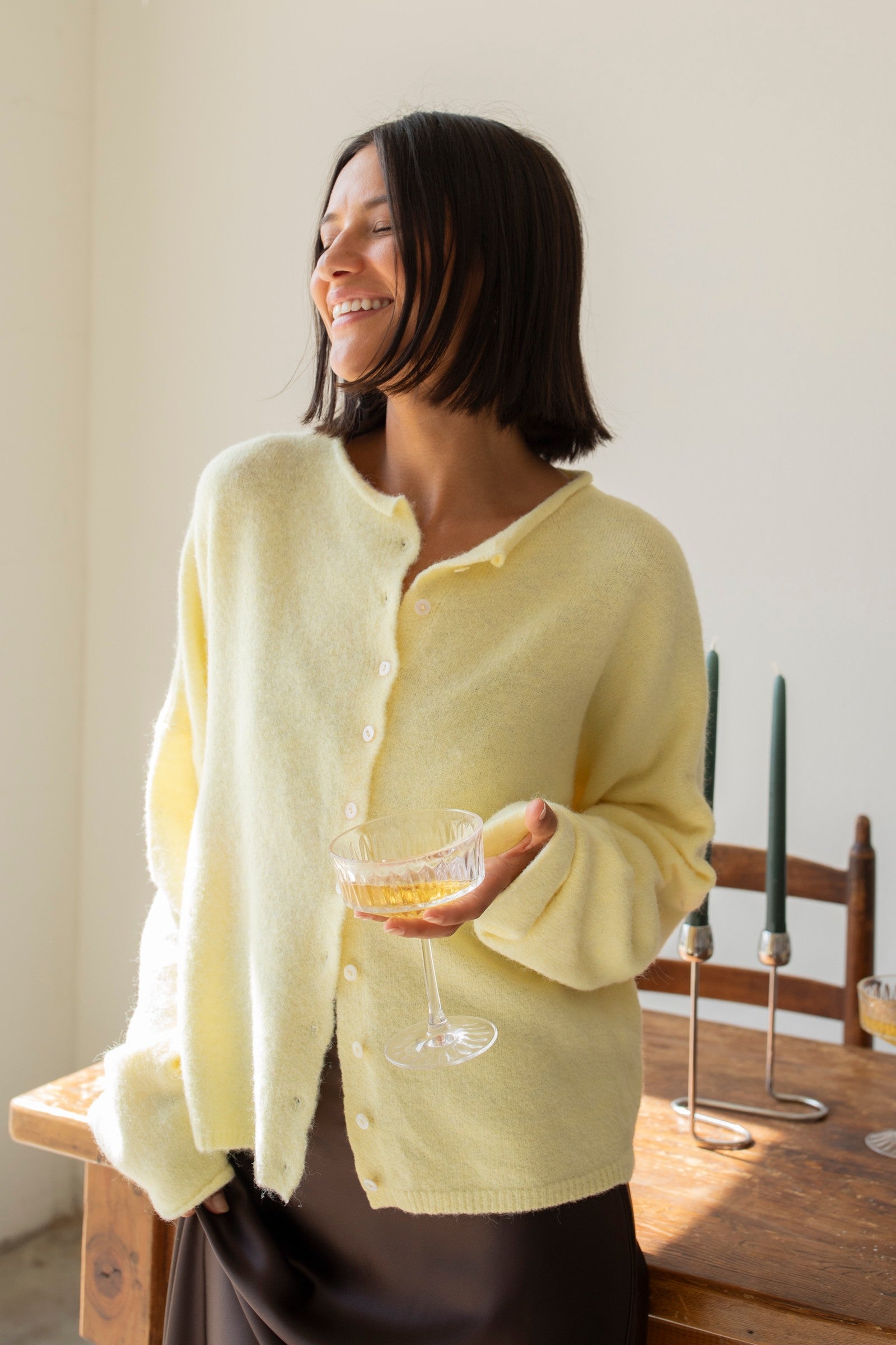 Woman wearing the Hailey Button Down Cardigan, also known as the Piper Cardigan — soft yellow lightweight knit with button front and rolled edges.