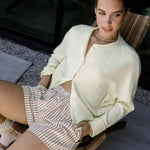 Woman sitting in a chair wearing the Piper Cardigan (Hailey Button Down Cardigan) — cozy and effortless layering piece.