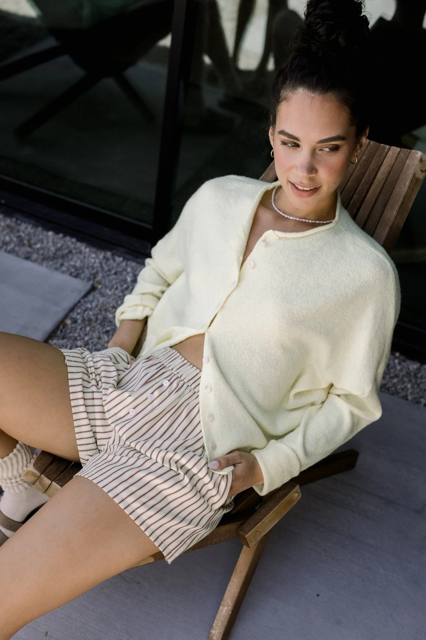 Woman sitting in a chair wearing the Piper Cardigan (Hailey Button Down Cardigan) — cozy and effortless layering piece.