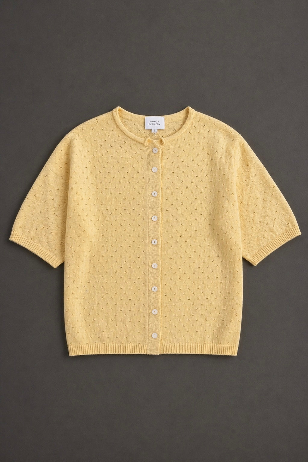 Piper Pointelle Cotton Button Down Cardigan in light yellow flat lay showing short sleeves, button front, and pointelle knit texture