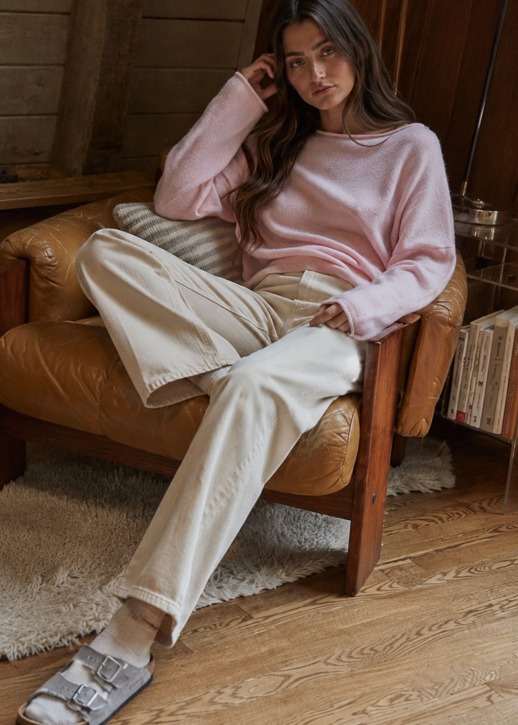 Model wearing the Piper Soft Knit Crew Sweater in Baby Pink with relaxed neutral pants - relaxed sitting pose