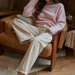 Model wearing the Piper Soft Knit Crew Sweater in Baby Pink with relaxed neutral pants - relaxed sitting pose