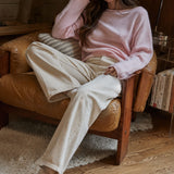 Model wearing the Piper Soft Knit Crew Sweater in Baby Pink with relaxed neutral pants - relaxed sitting pose