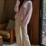 Model wearing the Piper Soft Knit Crew Sweater in Baby Pink with relaxed neutral pants - side view