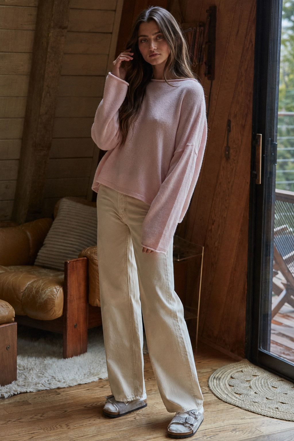Model wearing the Piper Soft Knit Crew Sweater in Baby Pink with relaxed neutral pants - side view