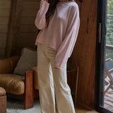 Model wearing the Piper Soft Knit Crew Sweater in Baby Pink with relaxed neutral pants - side view