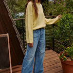 Model wearing the Piper Soft Knit Crew Sweater in Banana with relaxed neutral pants - side view