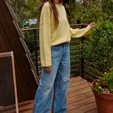 Model wearing the Piper Soft Knit Crew Sweater in Banana with relaxed neutral pants - side view