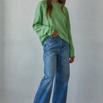 Model wearing the Piper Soft Knit Crew Sweater in Green with relaxed neutral pants - side view