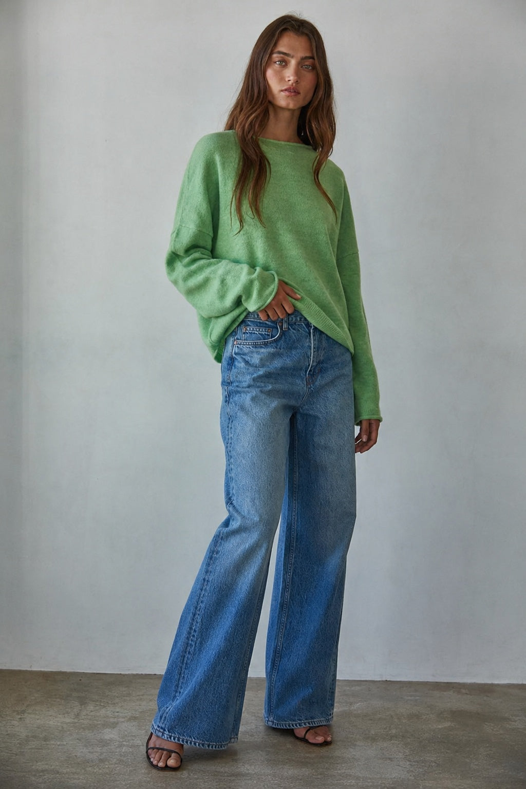 Model wearing the Piper Soft Knit Crew Sweater in Green with relaxed neutral pants - side view