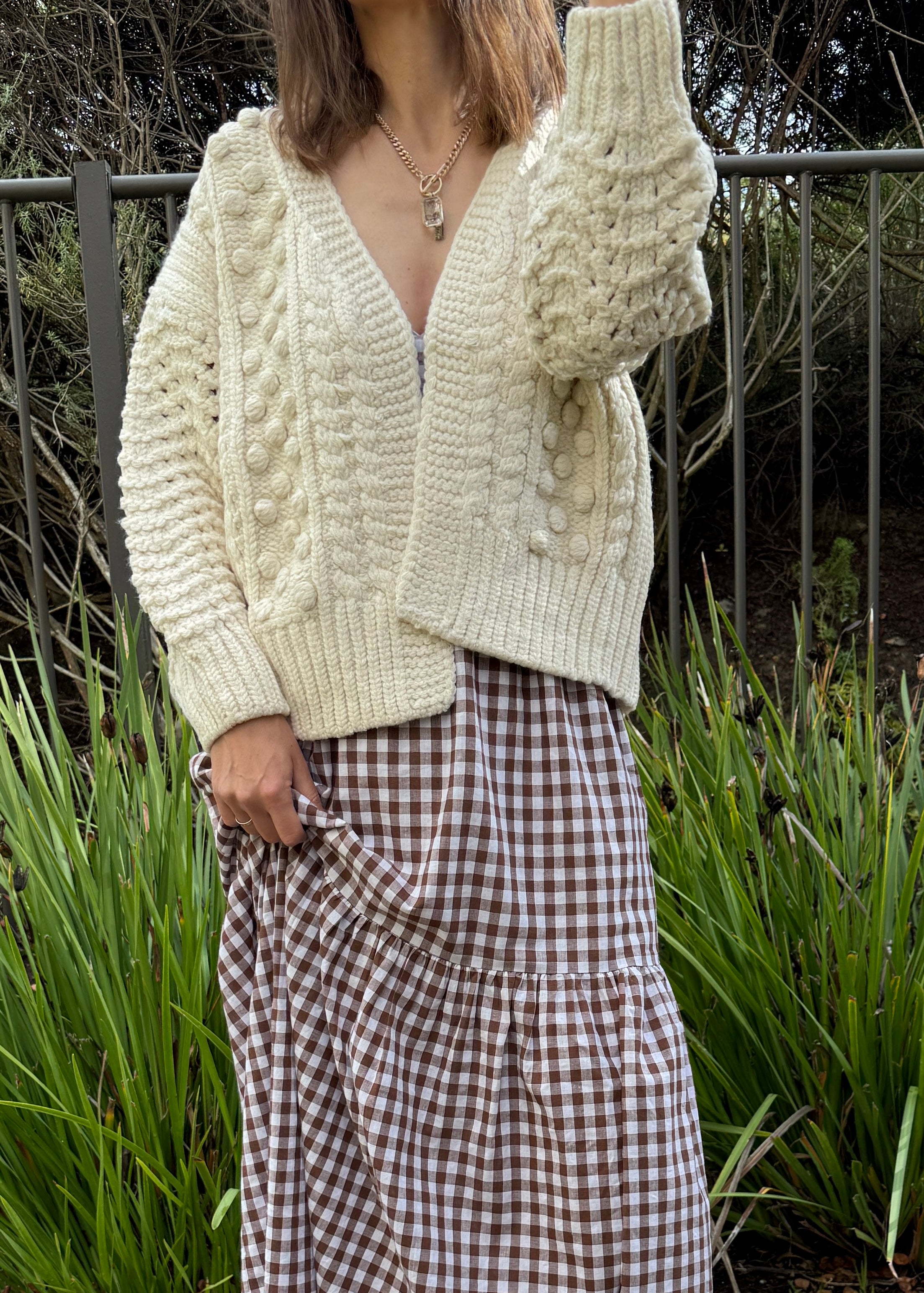 Styled front view of the ivory chunky knit cardigan layered over a dress