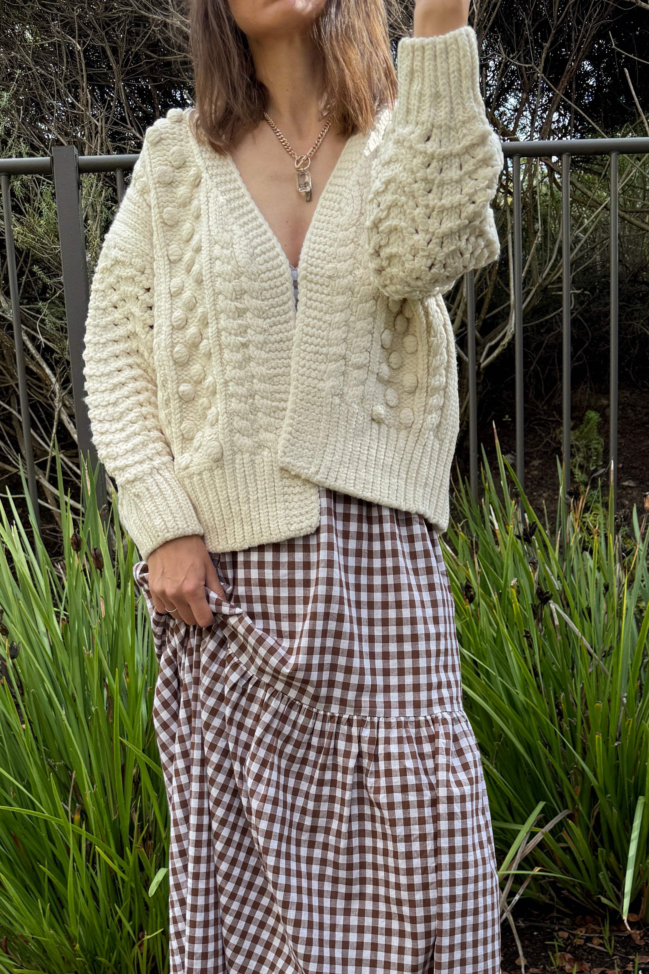 Styled front view of the ivory chunky knit cardigan layered over a dress