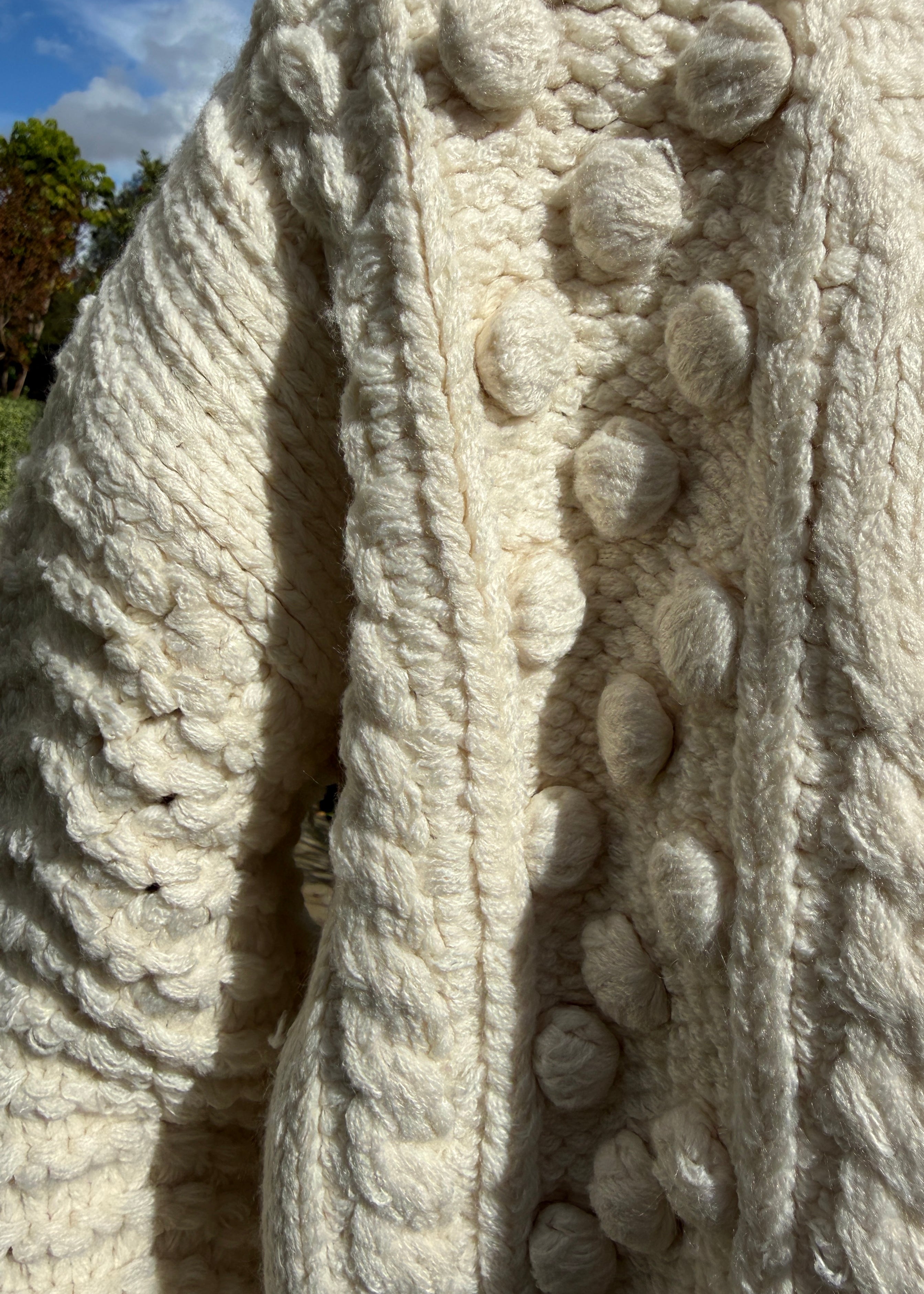 Close-up detail of the popcorn stitch texture on the ivory chunky knit cardigan