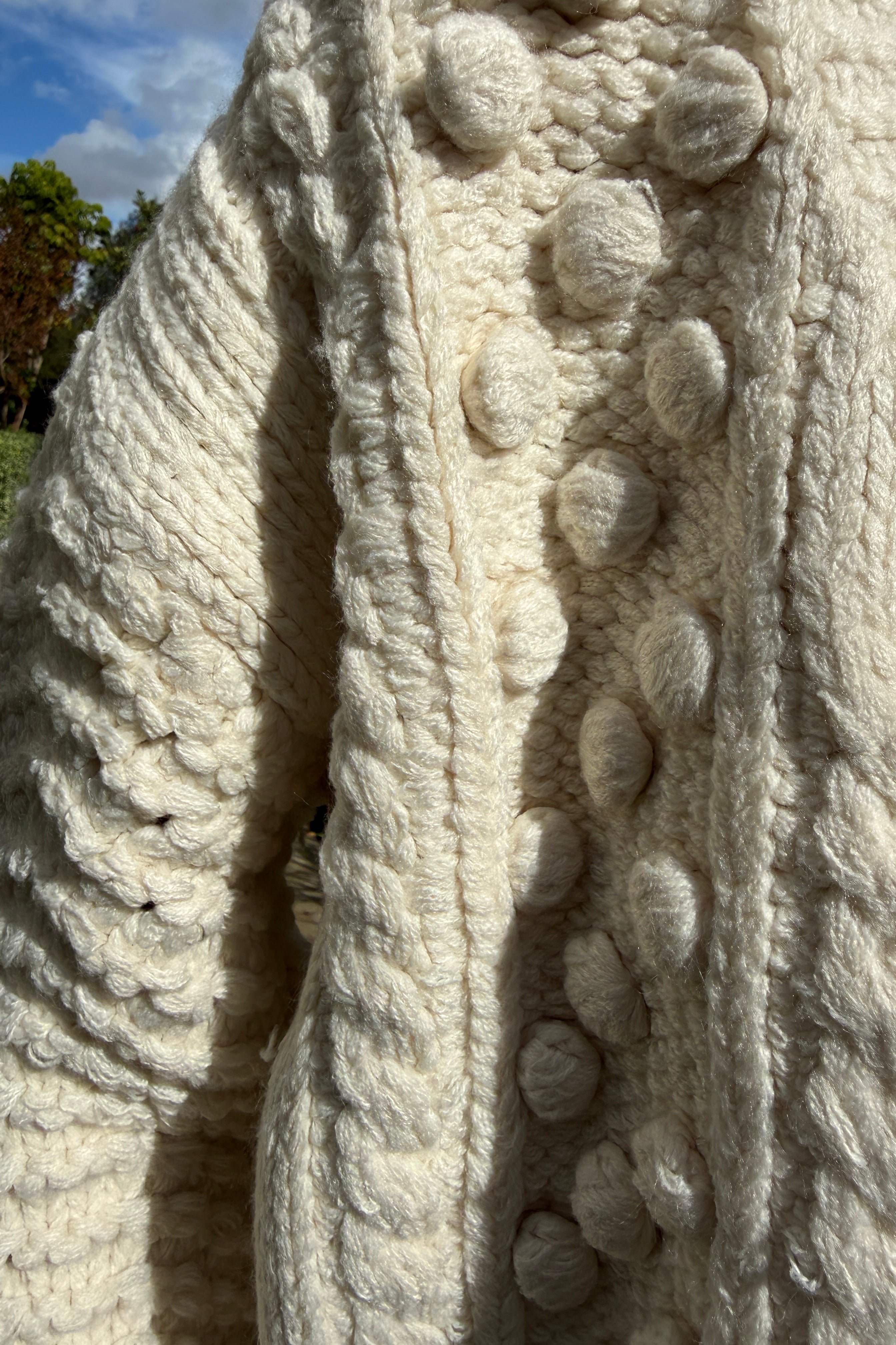 Close-up detail of the popcorn stitch texture on the ivory chunky knit cardigan