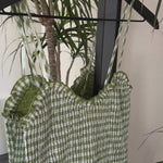 Detail video showing smocked top and gingham cotton texture on green maxi dress