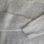 Flat lay video showing fuzzy knit texture of Carly pullover sweater in light grey