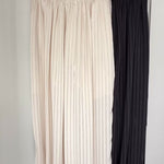 Close-up video showing the striped satin texture, elastic waistband, side drawstrings, pockets and balloon-leg shape of the beige Double Bubble pants.