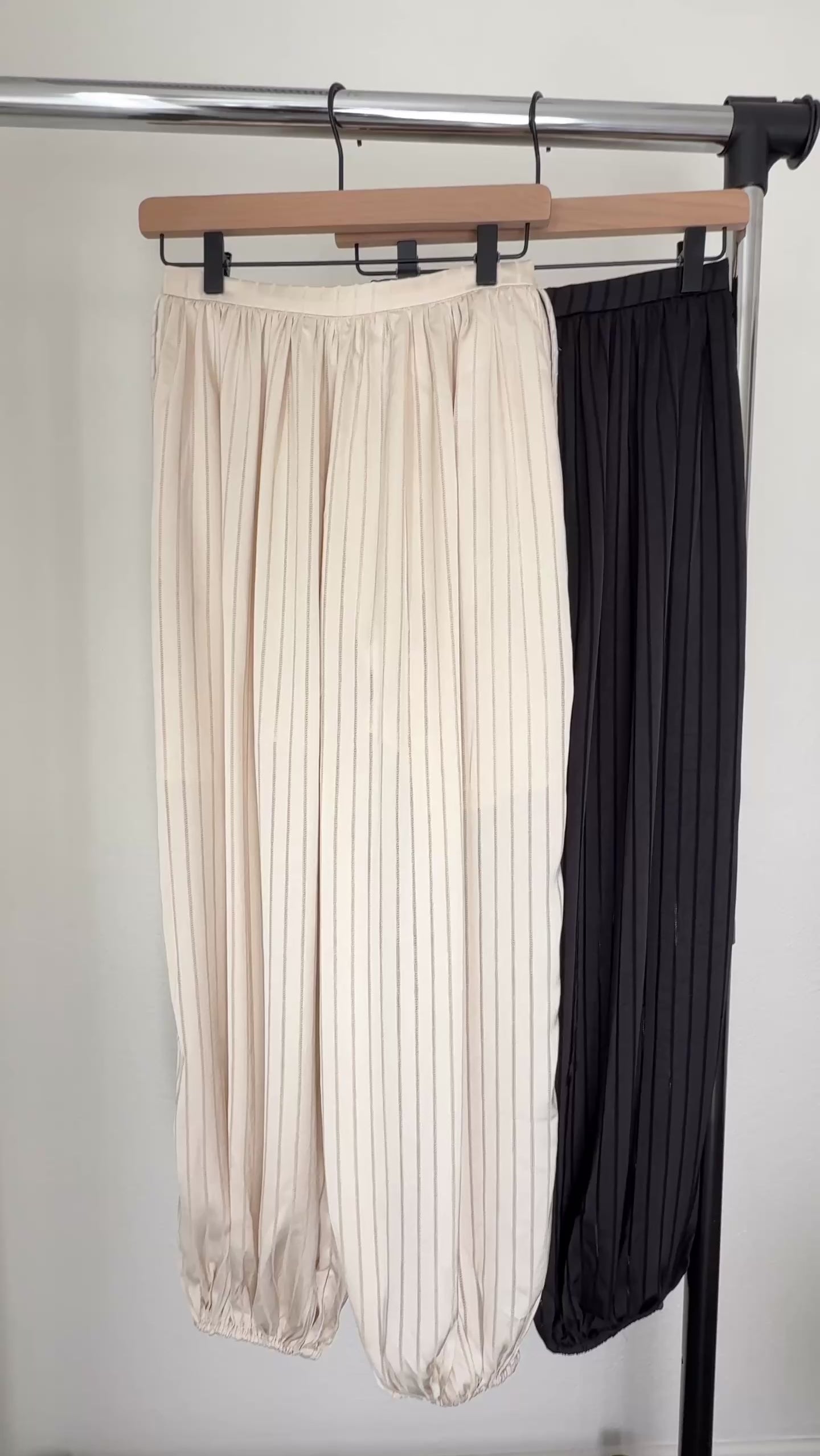 Close-up video showing the striped satin texture, elastic waistband, side drawstrings, pockets and balloon-leg shape of the beige Double Bubble pants.