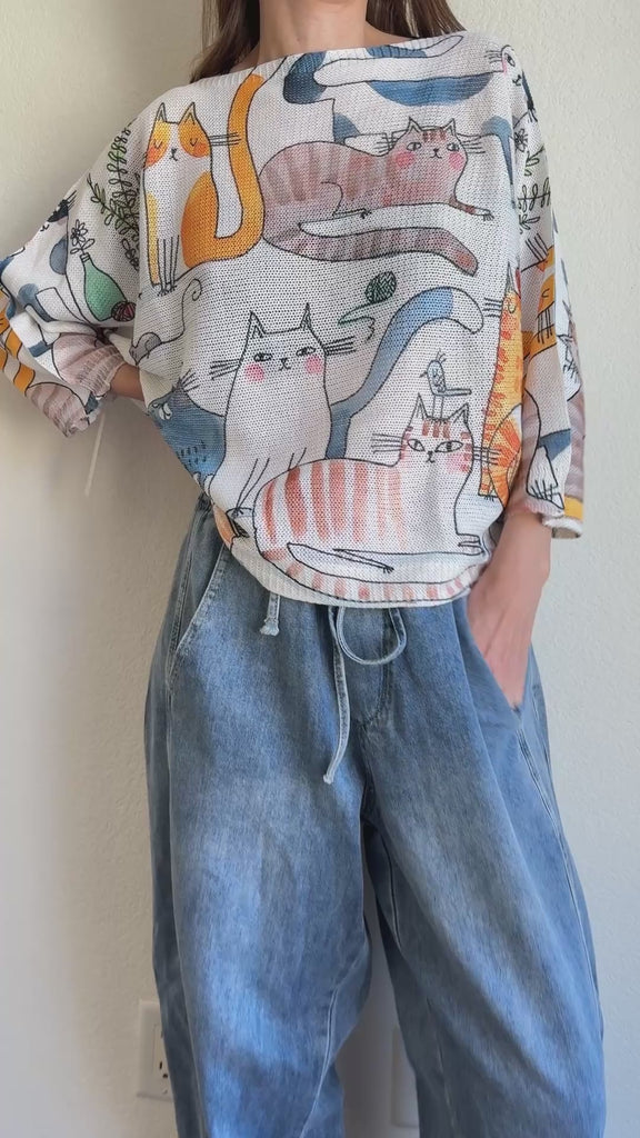 Model wearing the Livia Made in Italy batwing printed sweater with playful cats print, showing real fit and movement.