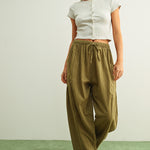 Woman wearing a white top and Quinn Loose Cotton Pinstripe Pants in green and stone with relaxed fit and elastic waist