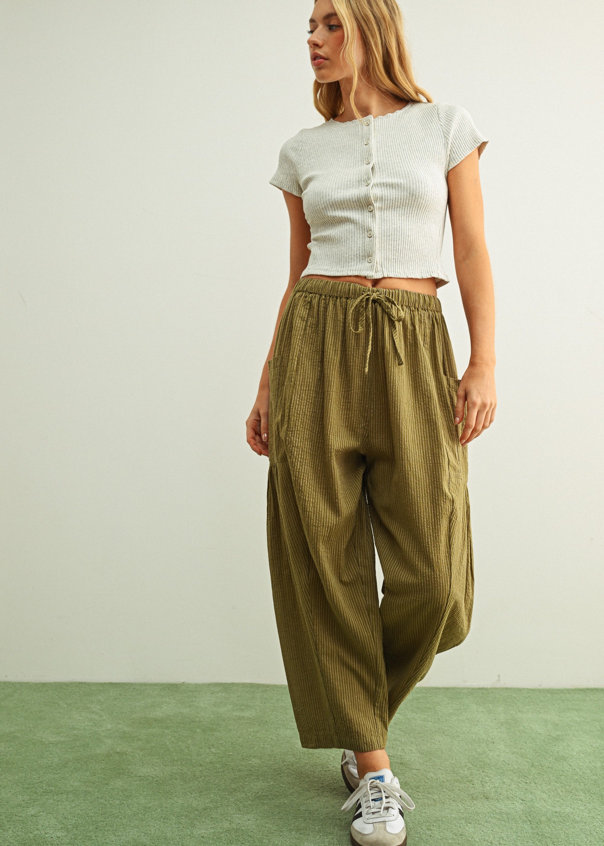 Woman wearing a white top and Quinn Loose Cotton Pinstripe Pants in green and stone with relaxed fit and elastic waist
