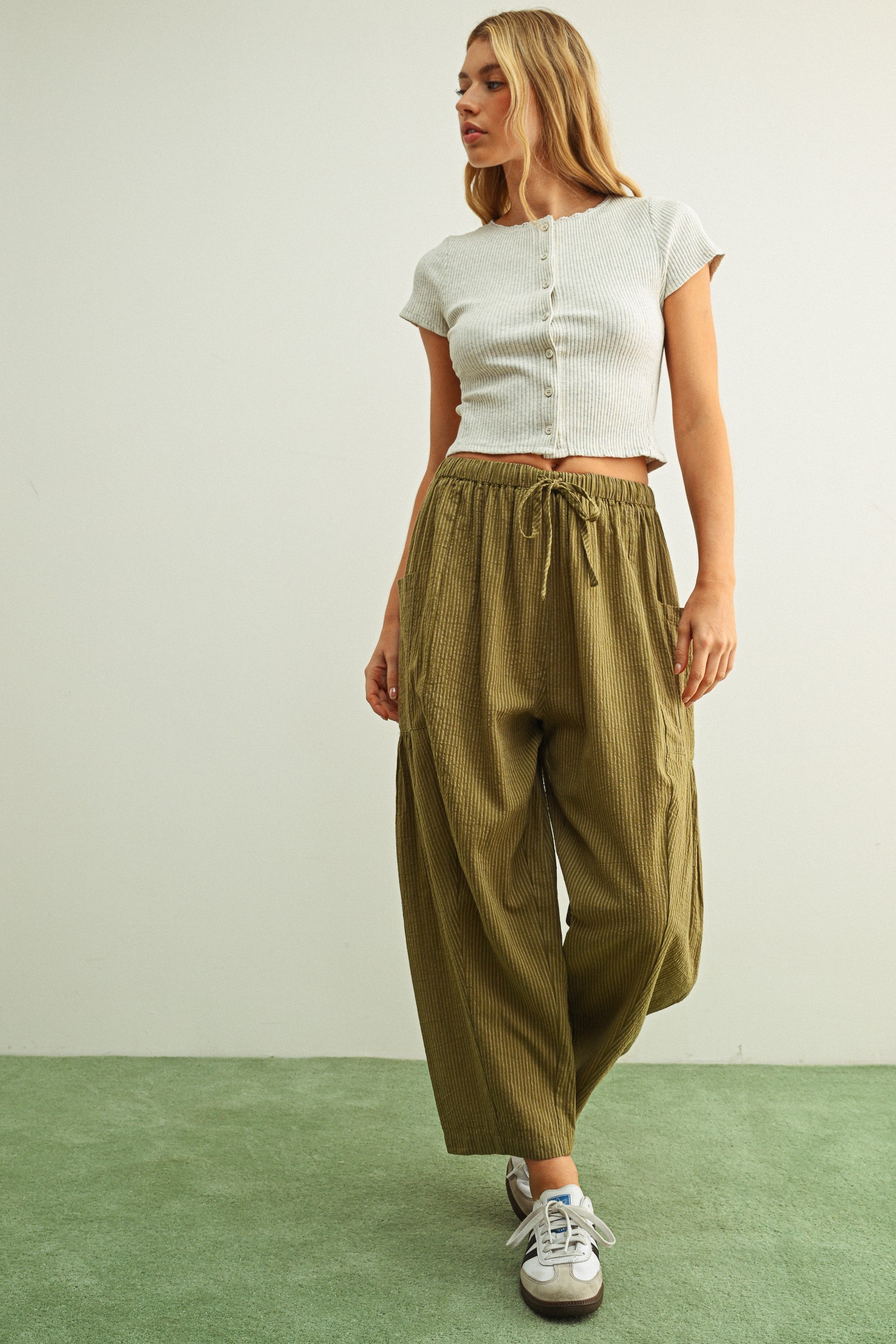 Woman wearing a white top and Quinn Loose Cotton Pinstripe Pants in green and stone with relaxed fit and elastic waist