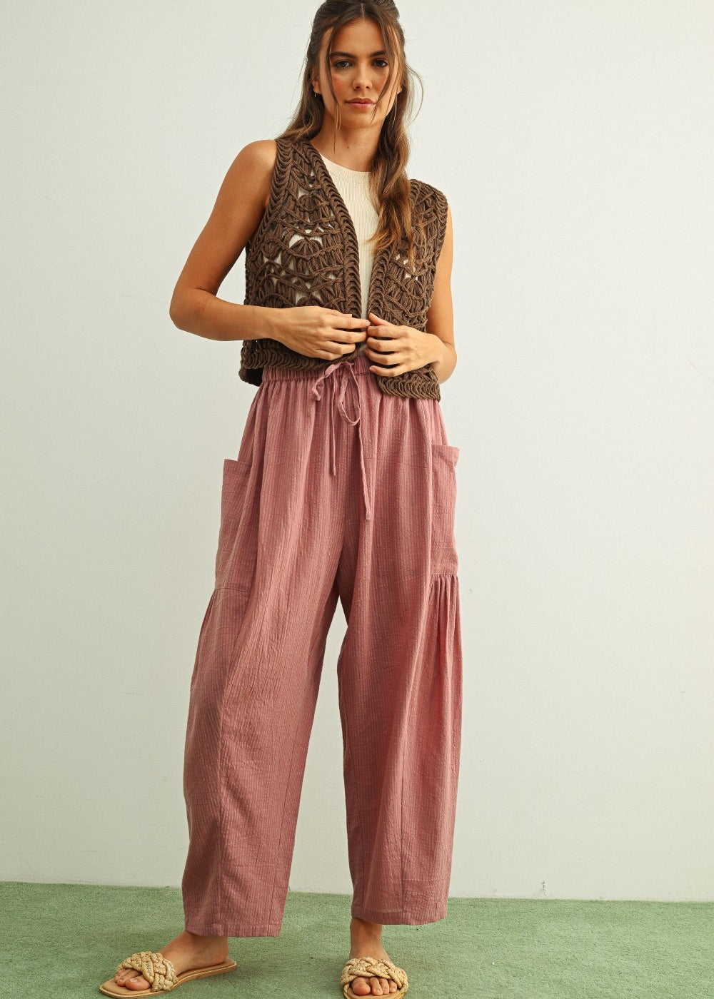 Woman wearing a brown patterned vest and  Quinn pink and stone pinstripe cotton harem pants with dropped pockets