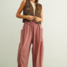 Woman wearing a brown patterned vest and  Quinn pink and stone pinstripe cotton harem pants with dropped pockets
